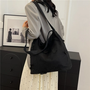 Minimalist black canvas tote bag with butterfly embroidery and wide shoulder strap