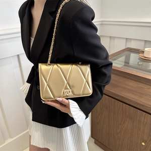 Borsa a tracolla trapuntata dorata con trama a rombi e catena elegante su un modello