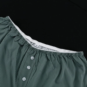 Detail of green and white striped neckline with ruffled lace and small white buttons