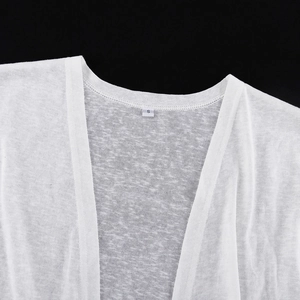 Dettaglio dello scollo a V e dell'etichetta S su un cardigan bianco in maglia leggera