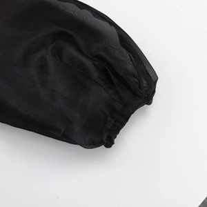 Detailed close-up of elastic cuffs on a black sheer puff sleeve blouse with mesh texture