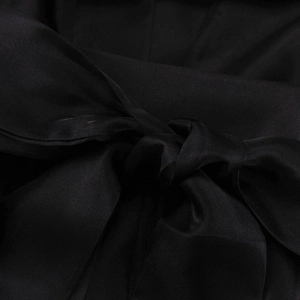 Macro shot of elegant black silk fabric with a knotted bow detail and soft satin texture