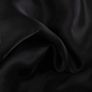 Detail of the high-quality glossy black satin fabric with smooth texture and soft folds