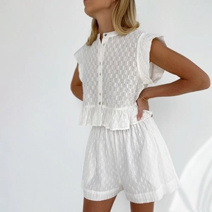 Detail of white textured jacquard fabric with ruffled hem and vintage buttons on shirt