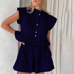 Detail of navy blue sleeveless top with white buttons and ruffled hemline coordinates