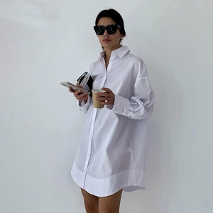 Détail de chemise blanche oversize en coton avec ourlet arrondi et poignets boutonnés