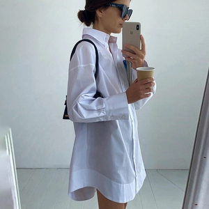Détail d'une chemise blanche en coton avec poignets larges et ourlet incurvé