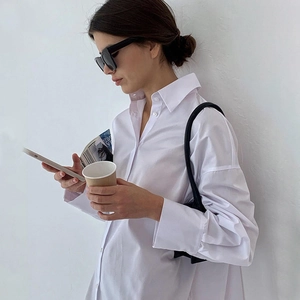 Détail d'une chemise blanche oversize en coton avec col à revers classique et épaules tombantes