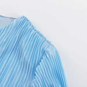 Dettaglio del tessuto a pieghe azzurro con cuciture sulle spalle e trama plissettata