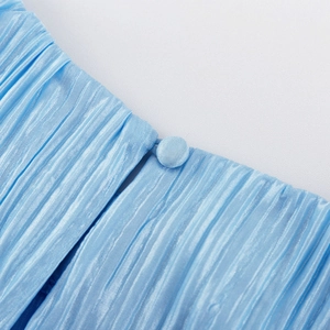Dettaglio del tessuto plissettato azzurro con fine trama verticale e bottone abbinato