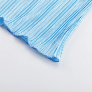 Dettaglio di tessuto in chiffon plissettato azzurro con pieghe verticali e bordi a volant