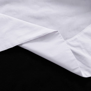 Gros plan détaillé de l'ourlet à double couture sur une chemise blanche à manches longues