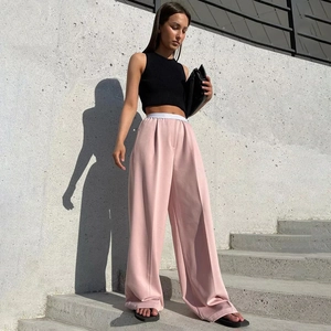 Détail du pantalon large rose à taille haute avec ceinture blanche et pli central
