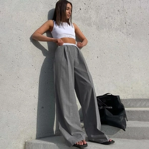 Détail du pantalon large gris à taille haute avec plis et texture de tissu drapé élégant