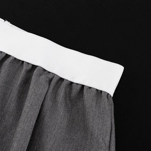 Détail macro du pantalon gris foncé avec ceinture élastique blanche et plis précis