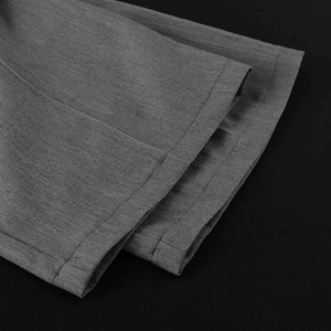 Gros plan détaillé de l'ourlet de pantalon gris foncé montrant la texture du tissu tissé
