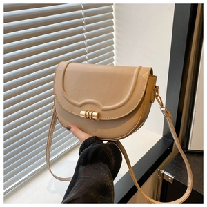 Nahaufnahme der beigen Satteltasche mit glattem Leder und goldenem Zylinderverschluss