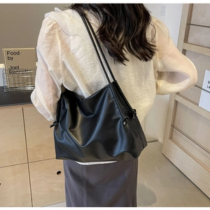 Dettaglio della borsa tote in pelle nera minimalista con lacci laterali a nodo
