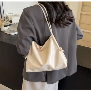 Détail du sac fourre-tout crème en cuir avec bandoulière nouée et design plissé souple