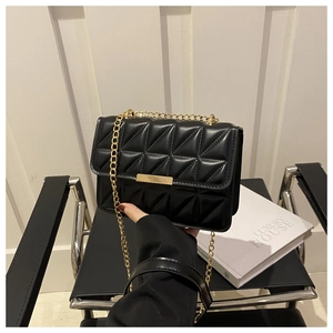 Detail of black quilted crossbody bag with golden clasp and elegant chain strap