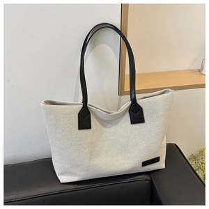 Detail of white canvas tote bag with black leather straps and Fashion patch on the surface