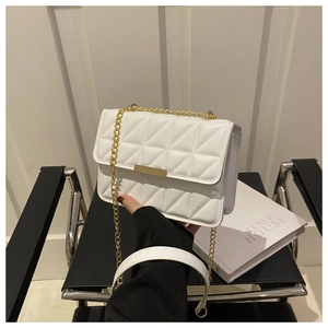 Close-up of quilted white leather texture and gold metal clasp on a luxury crossbody bag