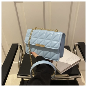 Detail of light blue quilted crossbody bag with gold chain strap and luxury metal clasp