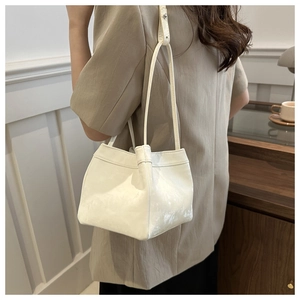 Detail view of the glossy white PU leather bucket bag with slim shoulder strap design