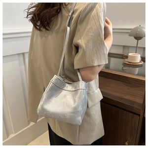 Silver bucket bag with shoulder strap shown on model in a cozy indoor lifestyle setting