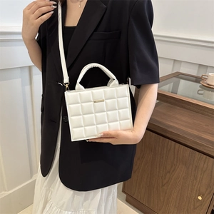 White rectangular quilted shoulder bag with top handle and gold metal bar detail