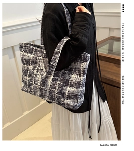 Detail of black and white tweed tote bag showing woven texture and spacious shoulder design
