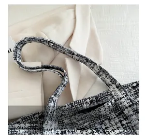 Detailed close-up of woven houndstooth texture and rounded handle of the chic tote bag