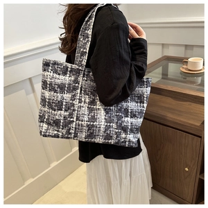 Close-up of black and white tweed tote bag showing textured woven fabric and large capacity