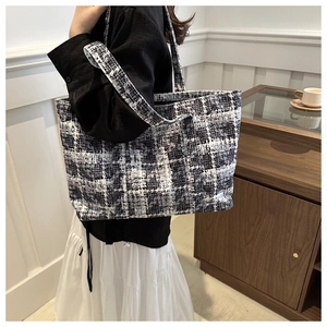 Lifestyle shot of woman wearing black and white checkered tweed tote bag over the shoulder