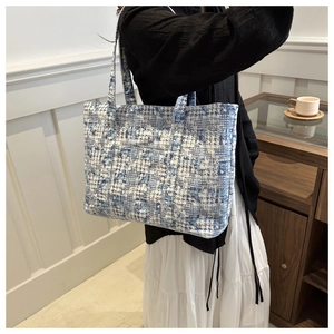 Detail of blue and white checkered tweed tote bag shown in a cozy lifestyle setting