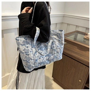 Chic blue and white patterned tote bag shown on model in a cozy minimalist indoor setting