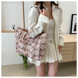 Detailed texture of brown plaid tweed tote bag shown on a model for casual daily use