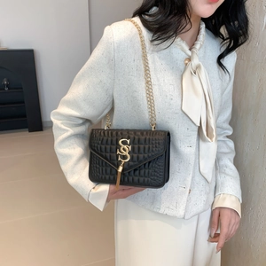 Quilted black crossbody bag with gold chain and crocodile texture on chic model