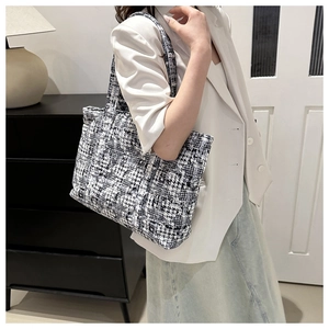 Detail of classic black and white tweed tote bag with elegant texture and reinforced strap