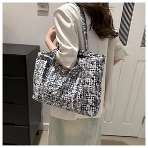 Rear view of a model wearing a textured black and white plaid tweed large tote bag