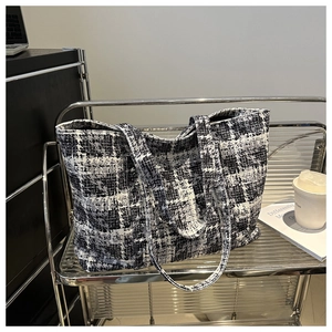 Close-up of woven houndstooth texture and double handles on a luxury tote bag