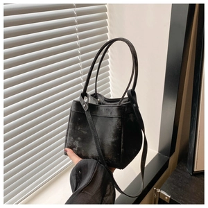 Detail of a vintage black bucket bag with textured finish and dual slim handles