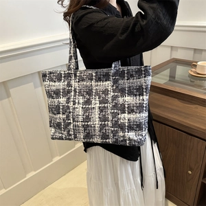 Classic black and white plaid tweed tote bag held by a model in a minimalist setting