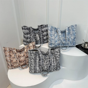 Classic tweed plaid tote bags in four colors displayed on a minimalist gallery stand