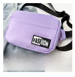 Detail of purple nylon crossbody bag with fashion label and adjustable strap on denim