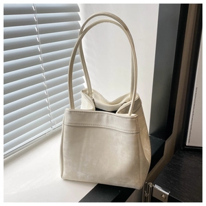 Detail shot of a minimalist cream-white bucket bag with fine leather texture on a windowsill