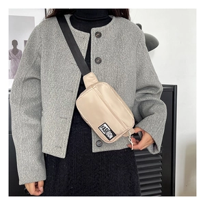 Detail view of stylish beige nylon crossbody bag with black FASHION logo and wide strap