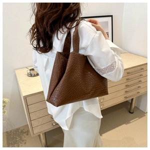 Close-up of brown oversized woven tote bag showing refined texture and retro style