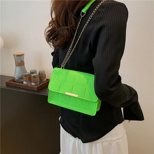 Neon green quilted crossbody bag with gold chain strap shown on model in modern home setting