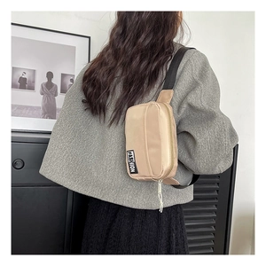 Detail of beige nylon crossbody bag with adjustable strap on gray sweater